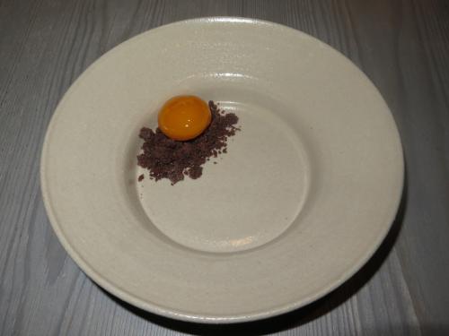An egg yolk preserved in sugar syrup served on a pile of crumbs made from pine tree bark An egg yolk preserved in sugar syrup served on a pile of crumbs made from pine tree bark